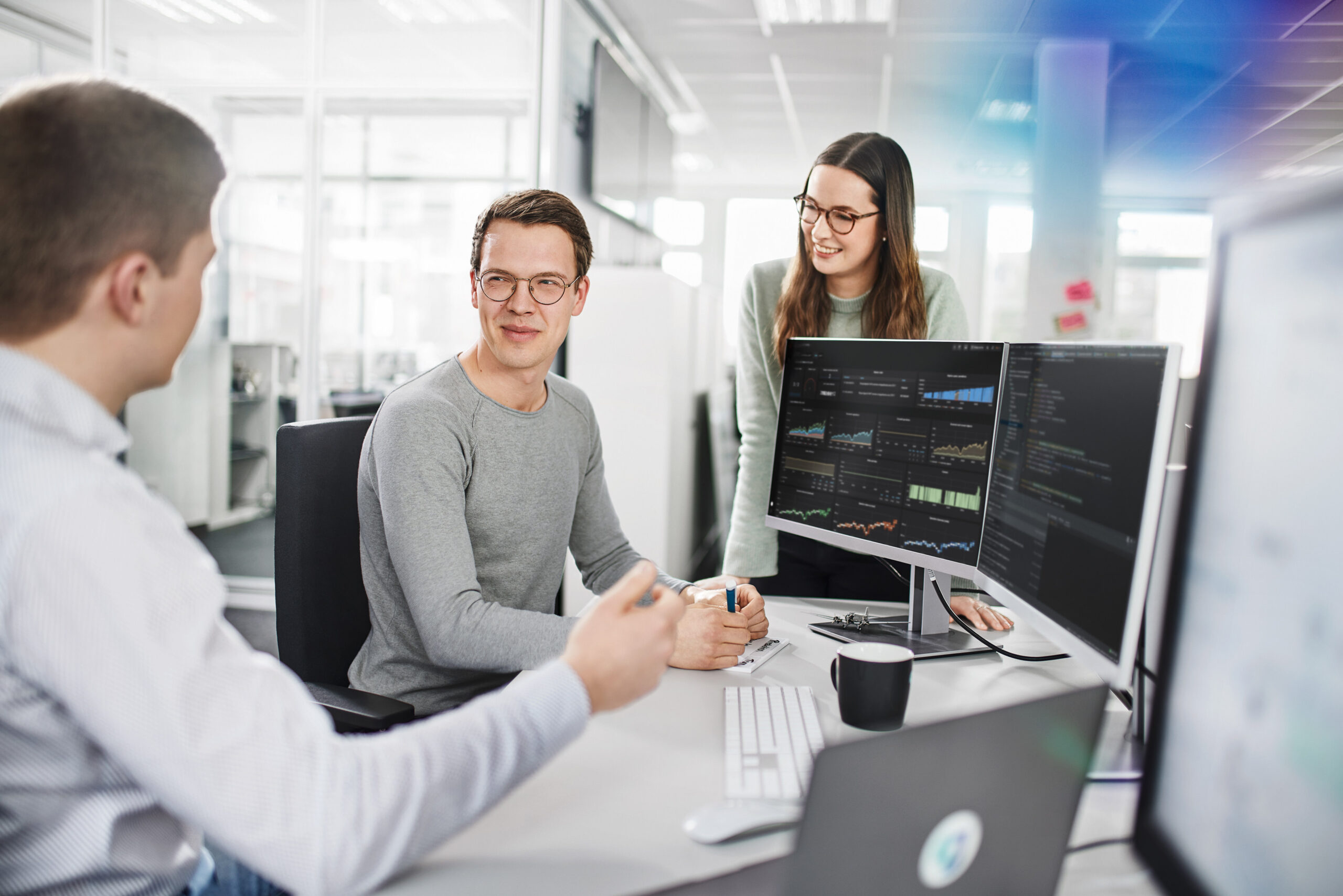Drei Mitarbeitende der Lufthansa Technik besprechen sich auf diesem Employer Branding Foto an einem Schreibtisch.