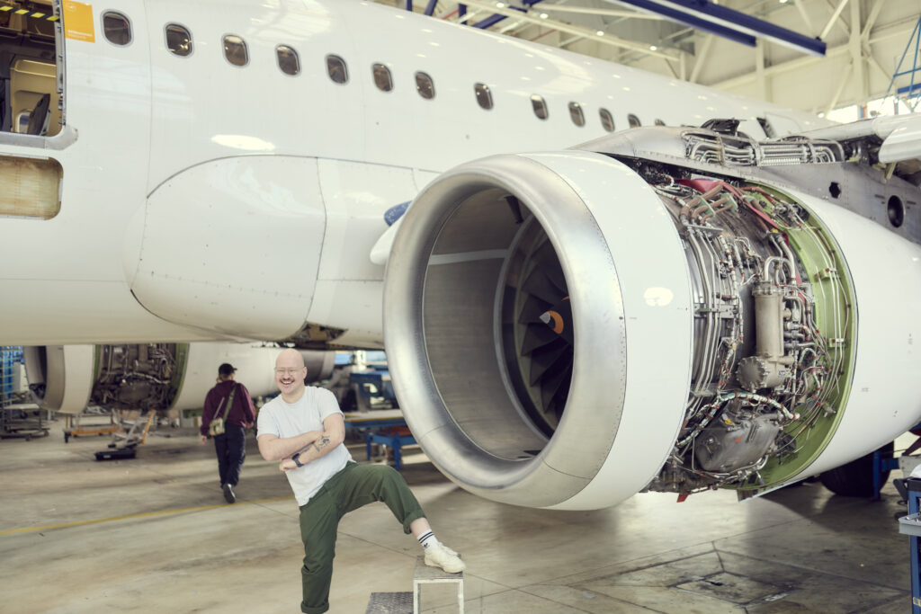 Hendrik Lüders macht Quatsch vor einem Flugzeug.
