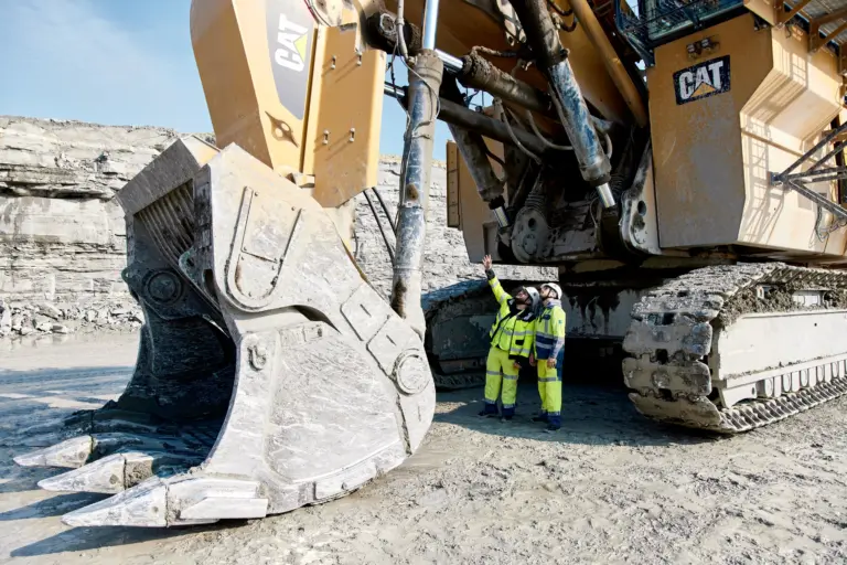Industriefoto zweier Mitarbeiter, die einen großen Bagger inspizieren