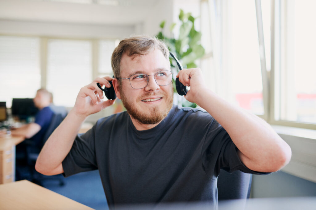 Ein junger Mann nimmt sein Headset ab.